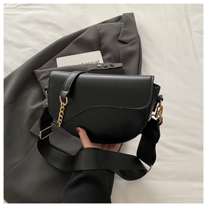 Detail of black saddle bag featuring golden chain accent and wide nylon shoulder strap