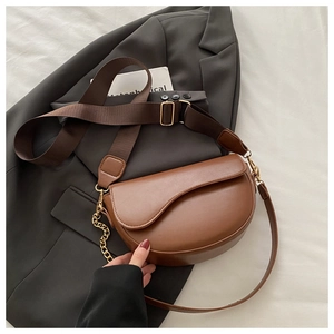 Detail of brown leather saddle bag with double shoulder straps and gold hardware