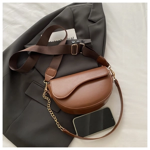 Brown semi-circle leather saddle bag with adjustable strap and decorative gold chain