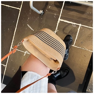 Dettaglio borsa tote in paglia intrecciata con strisce nere e tracolla in pelle marrone