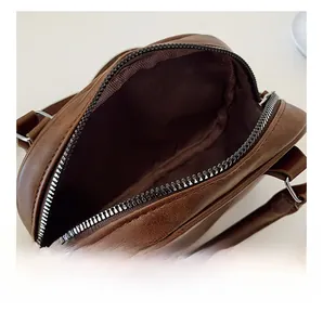 Détail d'un sac en cuir litchi marron avec zip argenté et intérieur en tissu spacieux
