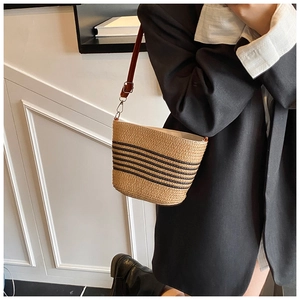 Détail du sac cabas en paille tissée à rayures noires et bandoulière en cuir brun
