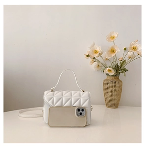 Detail of white quilted mini handbag with smartphone to show the compact size scale