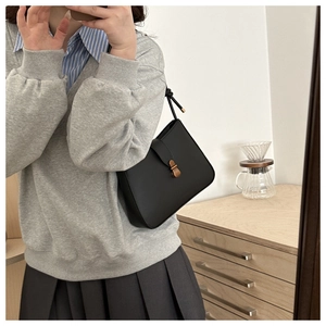 Mirror selfie showing a black leather shoulder bag with gold buckle and knotted strap detail