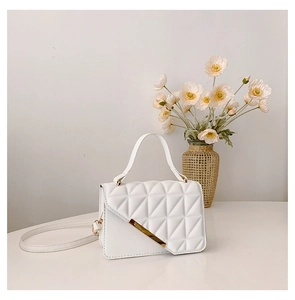 Detail shot of white quilted flap handbag with gold metal bar and adjustable strap