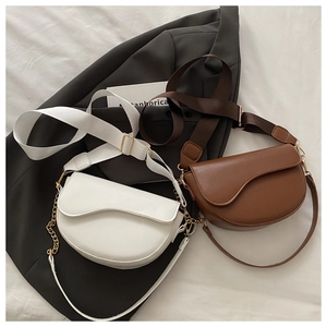 Flat lay of vintage saddle bags in white and brown leather with dual strap detail