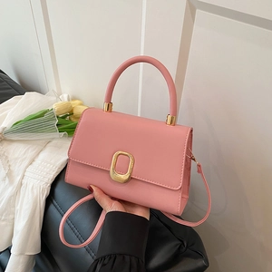 Pink PU leather square handbag with golden metal buckle and top handle shown on a black sofa