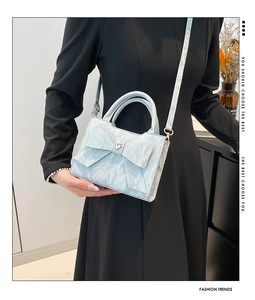Model wearing a light blue marble texture handbag with bow and heart crystal detail