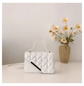 Detailed view of white quilted PU leather handbag with gold metal bar and textured finish