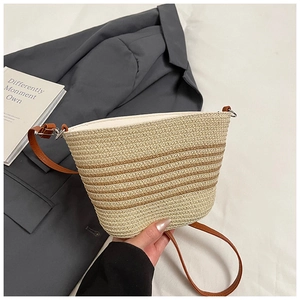 Dettaglio della borsa a secchiello in paglia con texture a righe e tracolla marrone