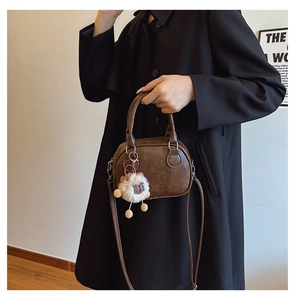 Détails du sac coquille vintage marron avec texture cuir et charm en peluche blanc
