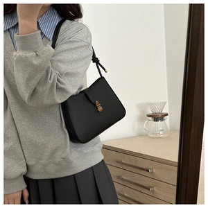 Detail of black vintage leather underarm bag featuring a metallic magnetic closure
