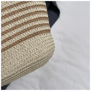 Dettaglio macro della trama in paglia a righe beige e marroni di una borsa da spiaggia