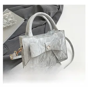 Detail of silver-grey pleated handbag with a large bow and heart rhinestone accent