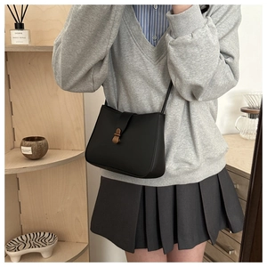 Detail of a vintage black matte crossbody bag featuring a retro bronze metal lock