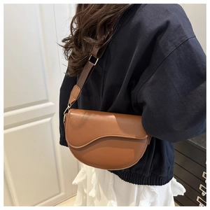 Detail of brown saddle bag featuring smooth faux leather and gold-tone hardware detail