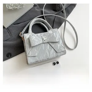 Detail of grey bow handbag with heart ornament and textured finish for women