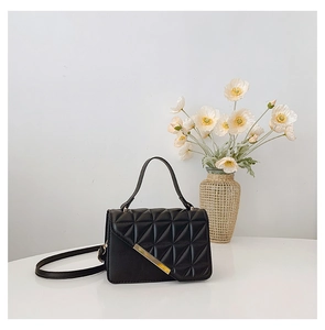 Close-up of black quilted small square bag with golden hardware and elegant handle