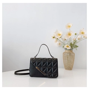 Detail of classic black quilted handbag with elegant gold metal trim and top handle