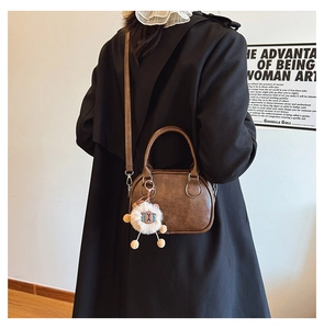 Detail of brown vintage handbag with Lucky Who embossed logo and white plush lamb charm