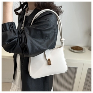 Close-up of white minimalist shoulder bag with vintage gold clasp and knot strap detail
