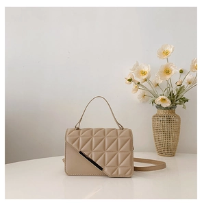 Detail of beige quilted shoulder bag with gold hardware and elegant floral background