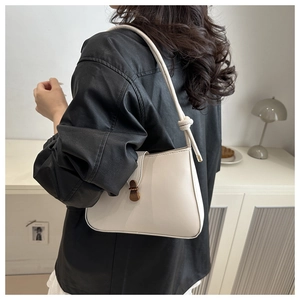 Detail showing vintage bronze metal buckle and leather texture of off-white shoulder bag