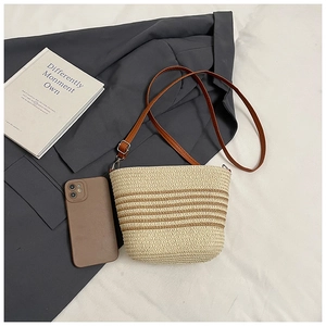 Dettaglio della borsa a tracolla in paglia beige con strisce marroni e cinturino in pelle
