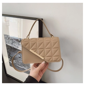 Detail of khaki quilted crossbody bag with golden metal bar and elegant hand-held handle