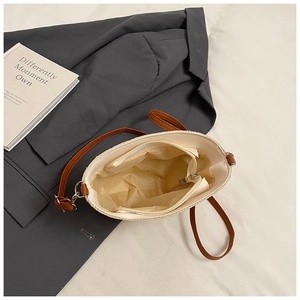 Vista dettagliata della borsa a secchiello in paglia intrecciata con tracolla in pelle e fodera