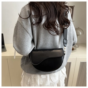 Close-up of matte black saddle bag with adjustable wide strap shown on a model
