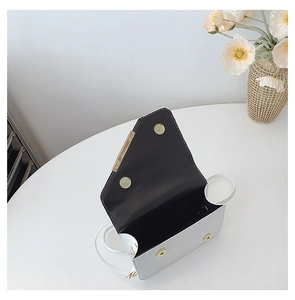 Detail view of the white crossbody bag featuring a gold metal trim and magnetic snap closure
