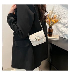 Détail du sac bandoulière crème matelassé avec fermoir cœur doré et bandoulière chaîne