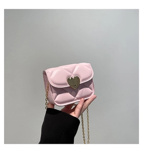 Macro detail of a mini pink quilted bag with a gold heart lock and elegant chain strap