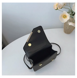 Detail of black crossbody bag showing asymmetric flap and double magnetic closure feature