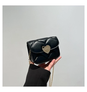 Detail of black quilted mini bag featuring a large gold heart-shaped metal lock and chain