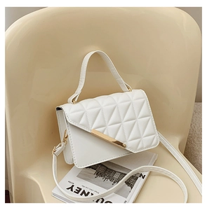 Close-up of white quilted crossbody bag with gold metal trim and flap closure