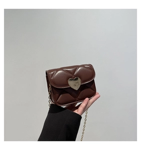 Close-up of brown quilted mini crossbody bag featuring a gold heart-shaped metal clasp
