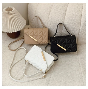 Detailed view of quilted square handbags in beige, black, and white with gold metal accents