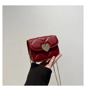 Detail of dark red mini quilted heart bag with a polished golden heart-shaped metal lock