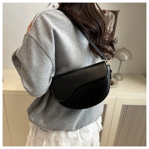 Modern black PU leather saddle bag showing realistic fit on model in minimalist setting