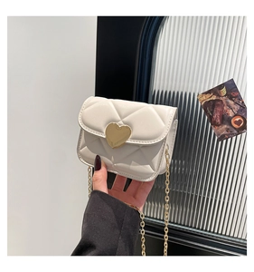 Detail view of mini white quilted square bag featuring a gold heart-shaped buckle and chain