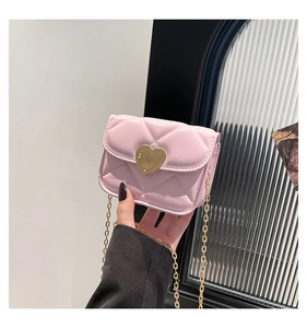 Detailed view of pink quilted mini crossbody bag with golden heart clasp in hand