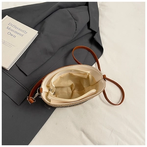 Vista interna della borsa in paglia con fodera beige e tasca con cerniera