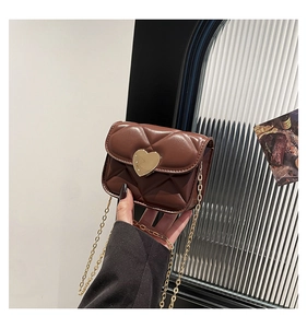 Close-up of quilted dark brown crossbody bag with gold heart-shaped lock and chain strap