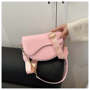 Detail view of pink saddle bag with matte leather and wide nylon shoulder strap