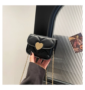Detailed shot of mini black quilted bag with heart-shaped gold buckle and chain
