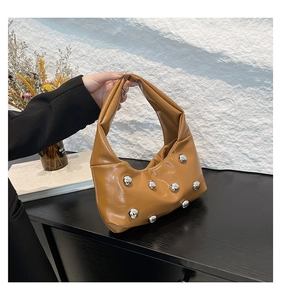 Detail of caramel crescent hobo bag with silver metallic sphere accents and leather texture