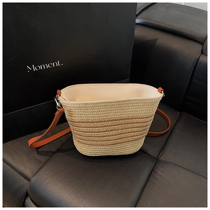 Dettaglio della borsa tote in paglia intrecciata con strisce marroni e tracolla sottile