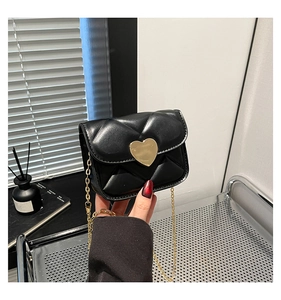 Detail of a mini black quilted leather bag with a gold heart clasp and chain strap